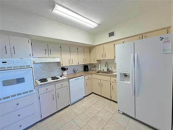 a kitchen with white cabinets and white appliances
