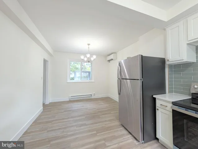 a view of a refrigerator in kitchen and an empty room