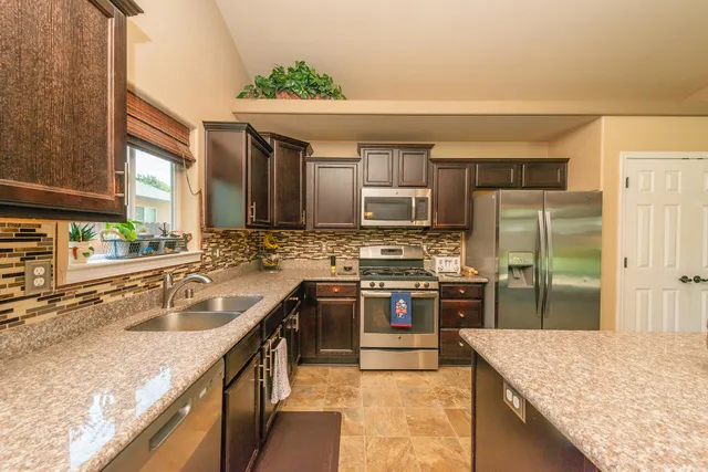 a large kitchen with stainless steel appliances granite countertop a stove and a sink