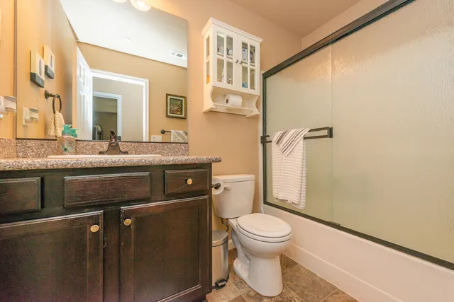 a bathroom with a granite countertop double vanity sink a mirror and shower