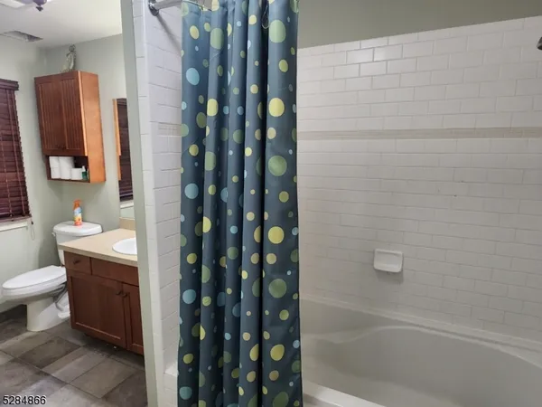 a bathroom with a granite countertop sink a toilet and shower