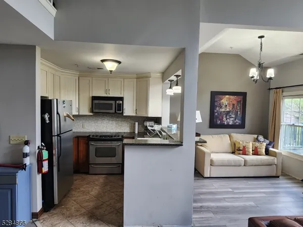 a living room with stainless steel appliances furniture and a flat screen tv