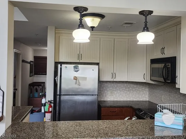 a kitchen with stainless steel appliances granite countertop a refrigerator a stove and a sink