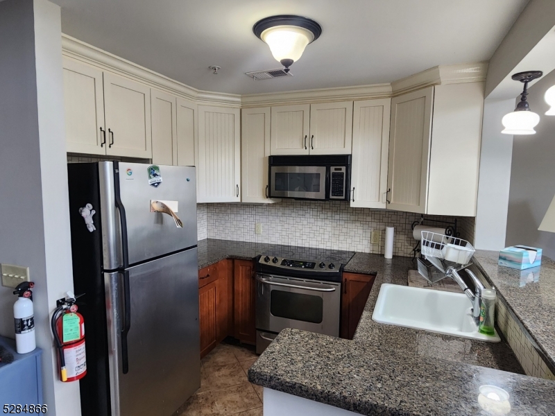 1 Pine Crescent, Unit 23 Vernon, NJ 07462 - Photo 9 of 28 a kitchen with stainless steel appliances granite countertop a refrigerator a stove and a sink