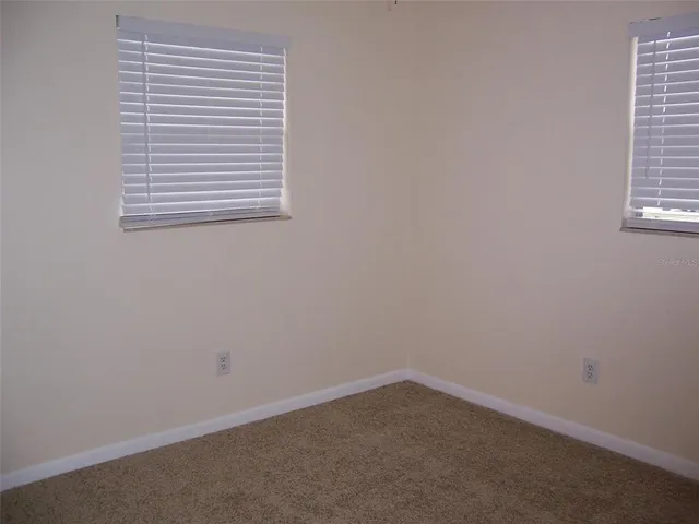 a view of an empty room with cabinet and windows