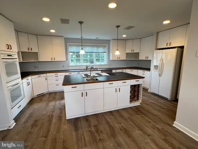 a kitchen with kitchen island a stove a sink and a wooden floor
