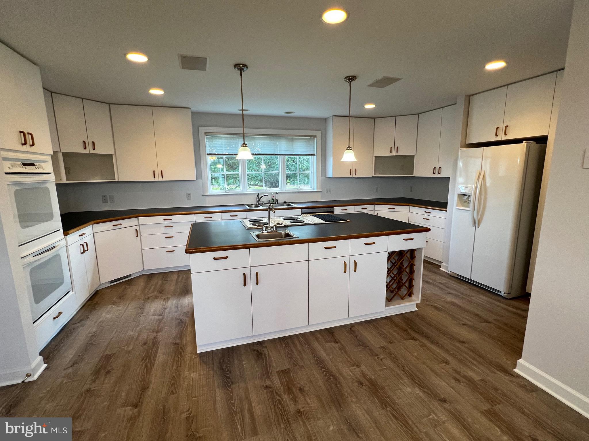 1343 Phoenix Road Sparks Glencoe, MD 21152 - Photo 12 of 57 a kitchen with wooden floor white cabinets and stainless steel appliances