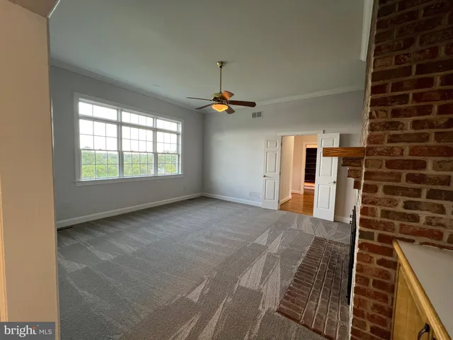 an empty room with wooden floor fireplace and windows