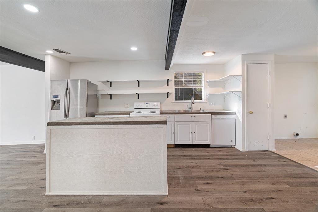 2413 Simpson Street Paris, TX 75460 - Photo 3 of 15 a kitchen with a sink a stove a refrigerator and white cabinets