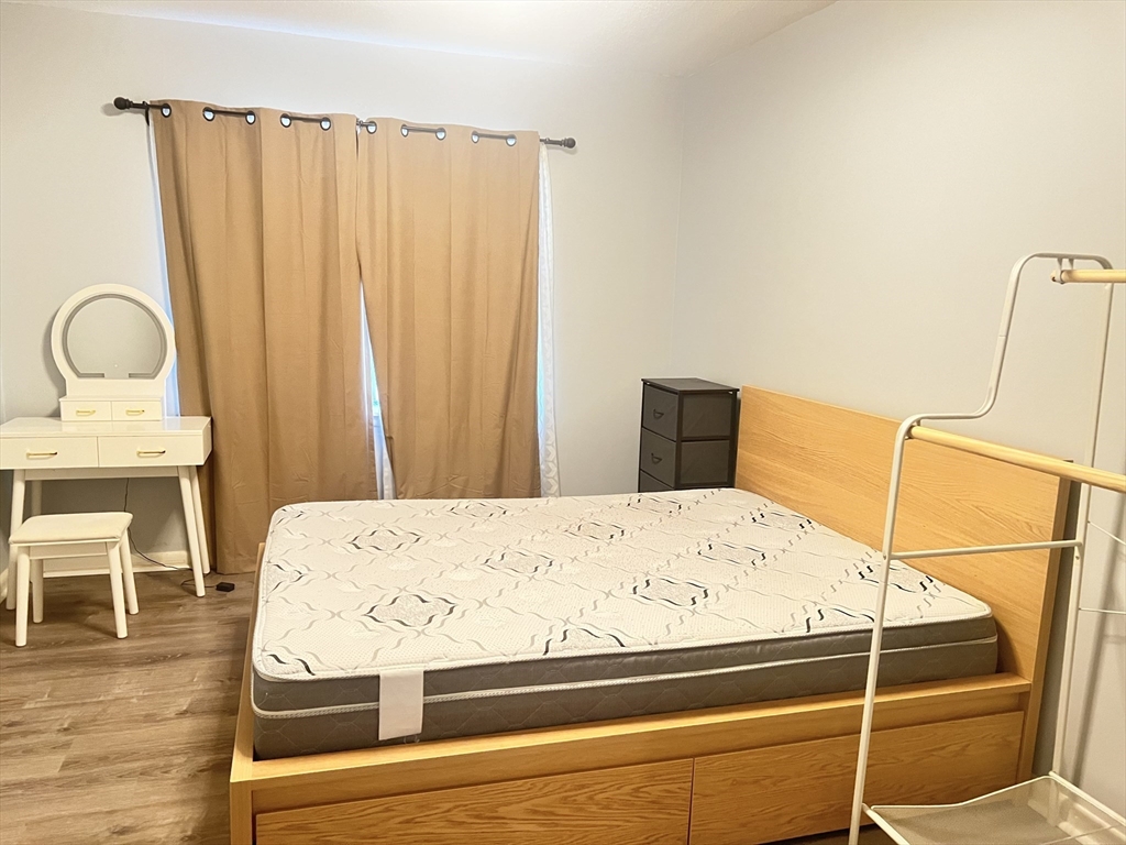 11 Lake Shore Court, Unit 2 Boston, MA 02135 - Photo 4 of 9 a bed sitting in a bedroom next to a window with wooden floor