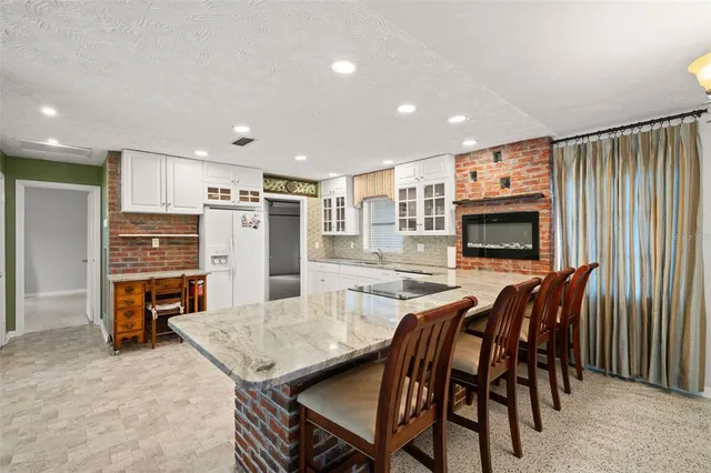 a kitchen with stainless steel appliances granite countertop table chairs microwave and refrigerator