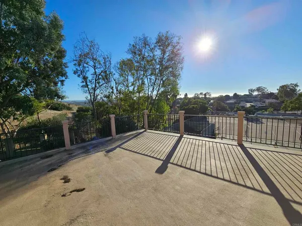 a view of backyard with large trees and wooden fence
