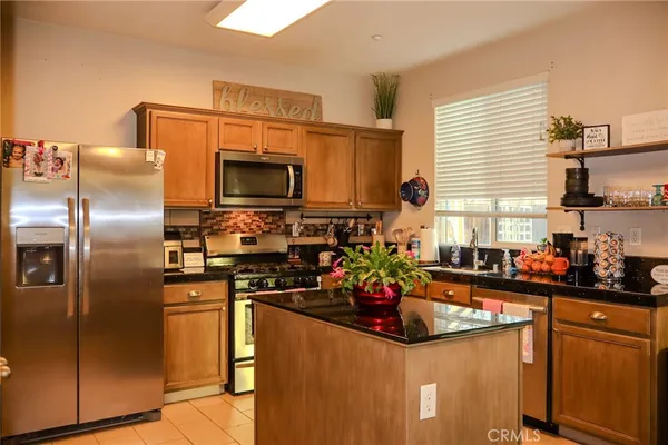 a kitchen with stainless steel appliances kitchen island granite countertop a sink stove and refrigerator