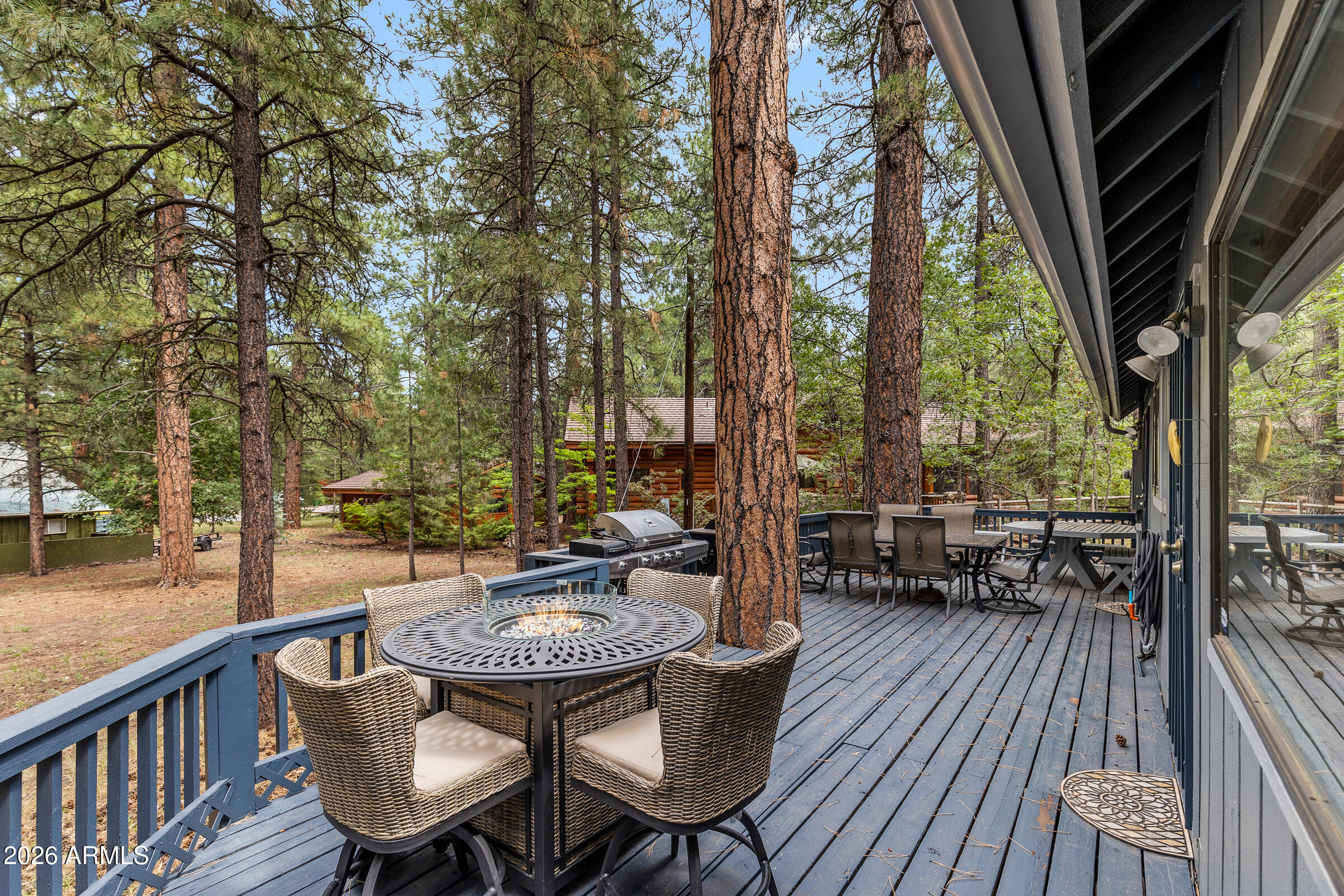 a view of a patio with table and chairs and wooden floor with a barbeque