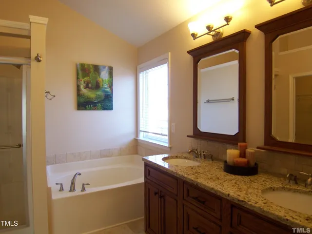 a bathroom with a granite countertop tub sink and mirror