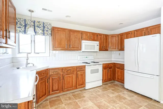a kitchen with stainless steel appliances granite countertop a refrigerator sink and wooden cabinets