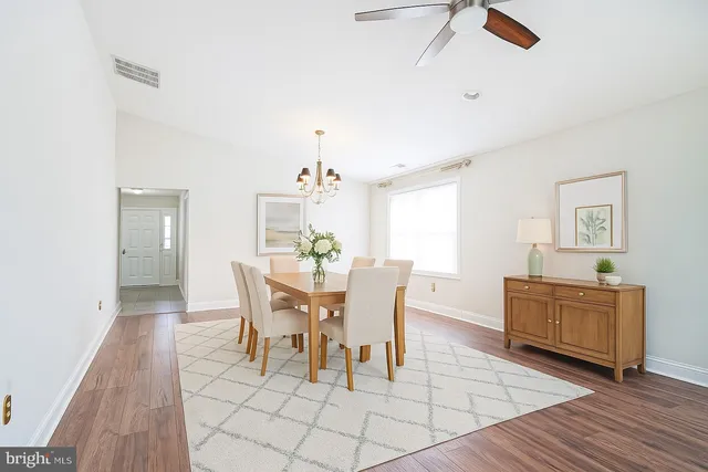 a dining room with furniture a chandelier and wooden floor