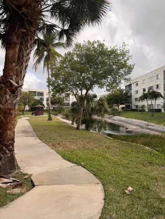 a view of swimming pool with a yard and palm trees