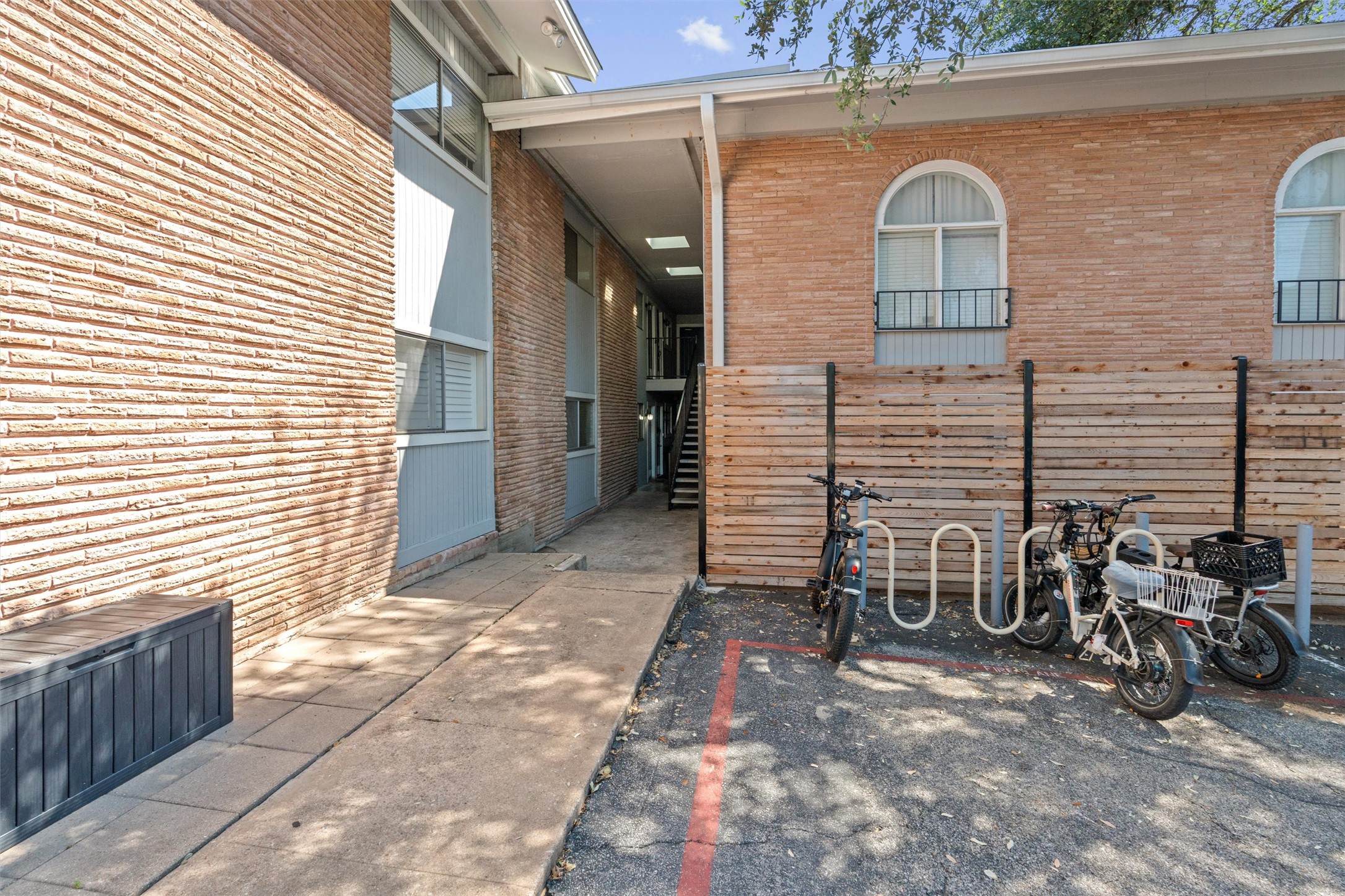 2208 Enfield Road, Unit 10500 Austin, TX 78703 - Photo 6 of 34 Brick exterior building featuring arched windows, a covered walkway, and a dedicated bike rack area