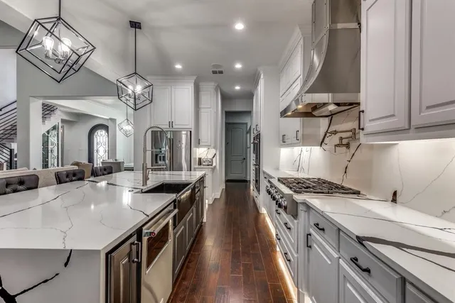 a kitchen with stainless steel appliances granite countertop a stove a sink dishwasher and a refrigerator with wooden floor