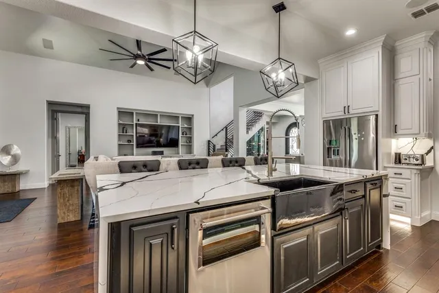 a kitchen with stainless steel appliances granite countertop a sink a stove and a wooden floor
