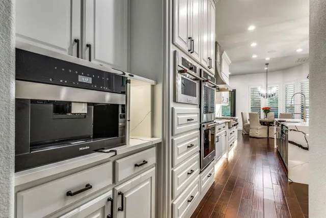 a kitchen with stainless steel appliances white cabinets and wooden floor