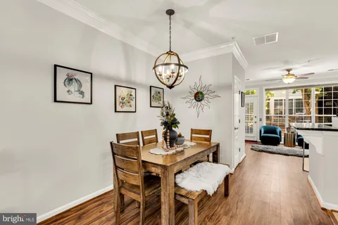 a dining room with wooden floor a chandelier a wooden table and chairs