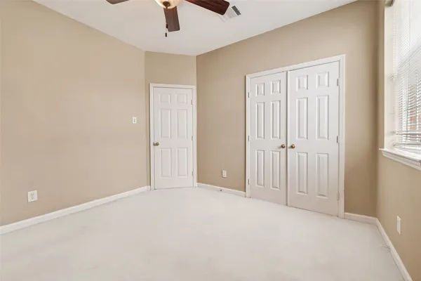 an empty room with windows and ceiling fan