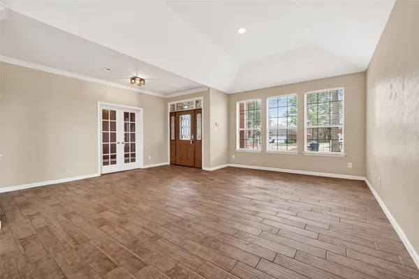 a view of an empty room with a window and wooden floor