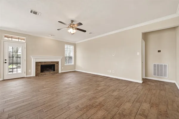 a view of an empty room with wooden floor fireplace and a window