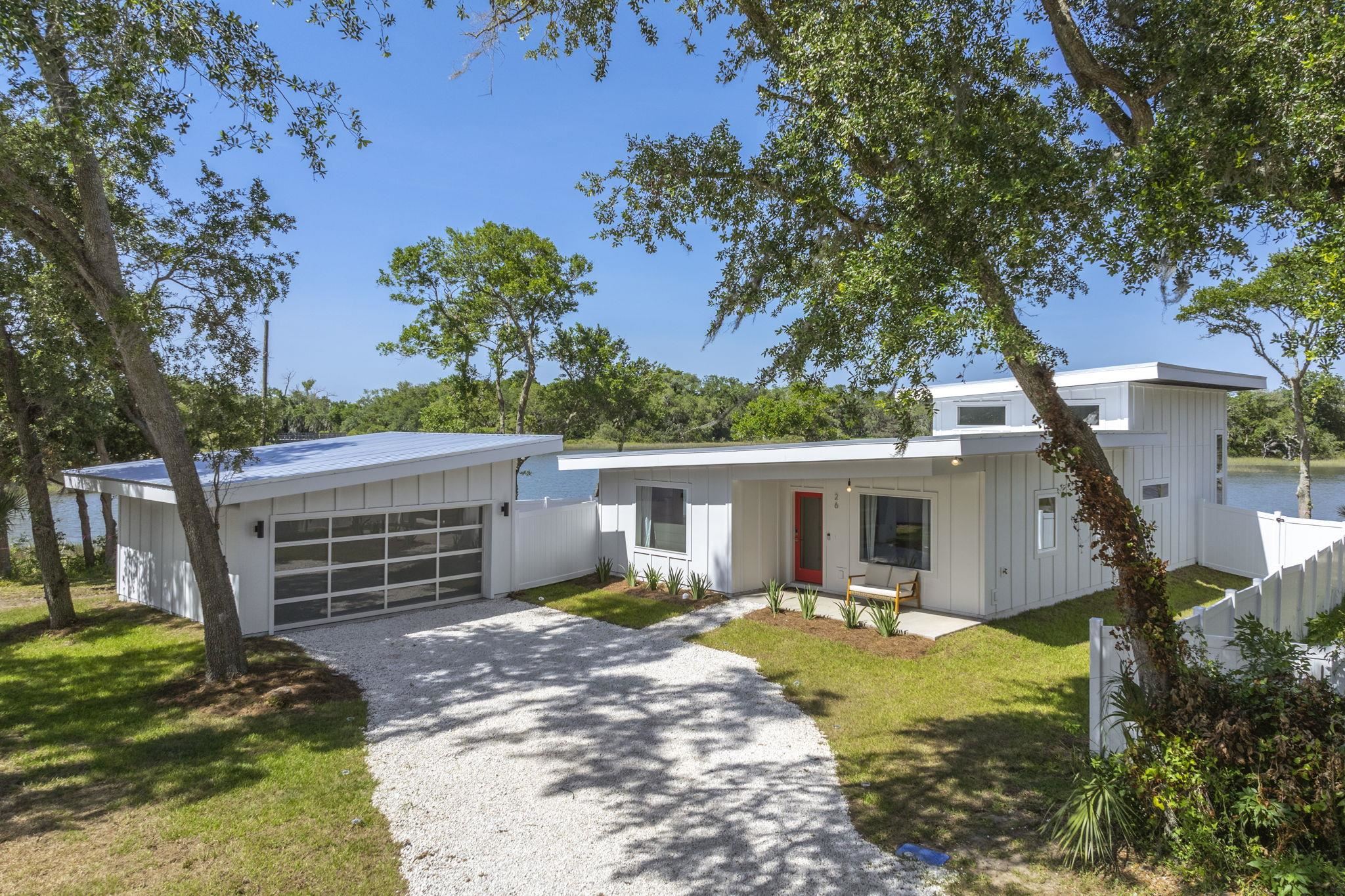 a view of a house with a small yard and a large tree