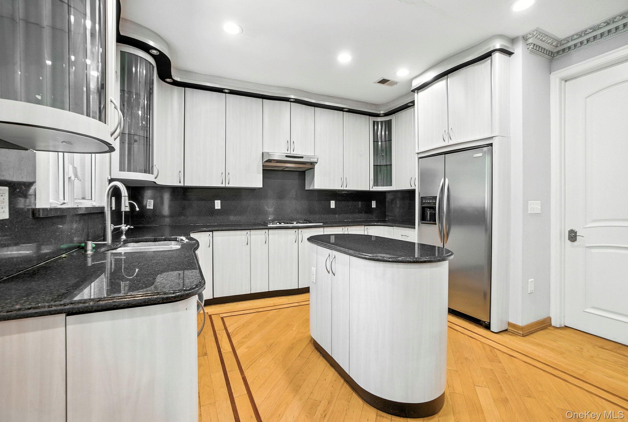 77-16 Kew Forest Lane Queens, NY 11375 - Photo 12 of 28 a kitchen with stainless steel appliances granite countertop a sink refrigerator and cabinets