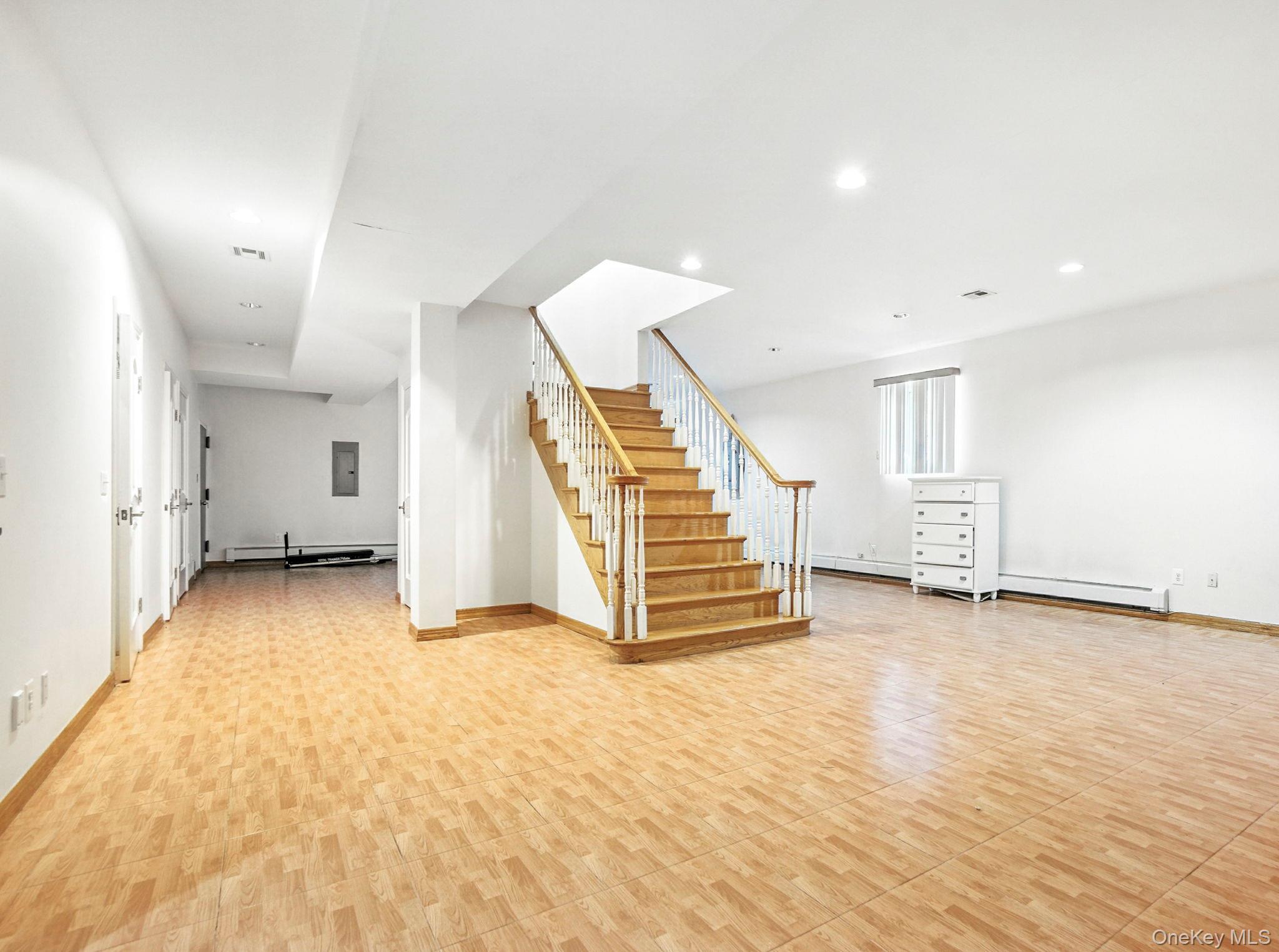 77-16 Kew Forest Lane Queens, NY 11375 - Photo 18 of 28 an empty room with wooden floor and stairs