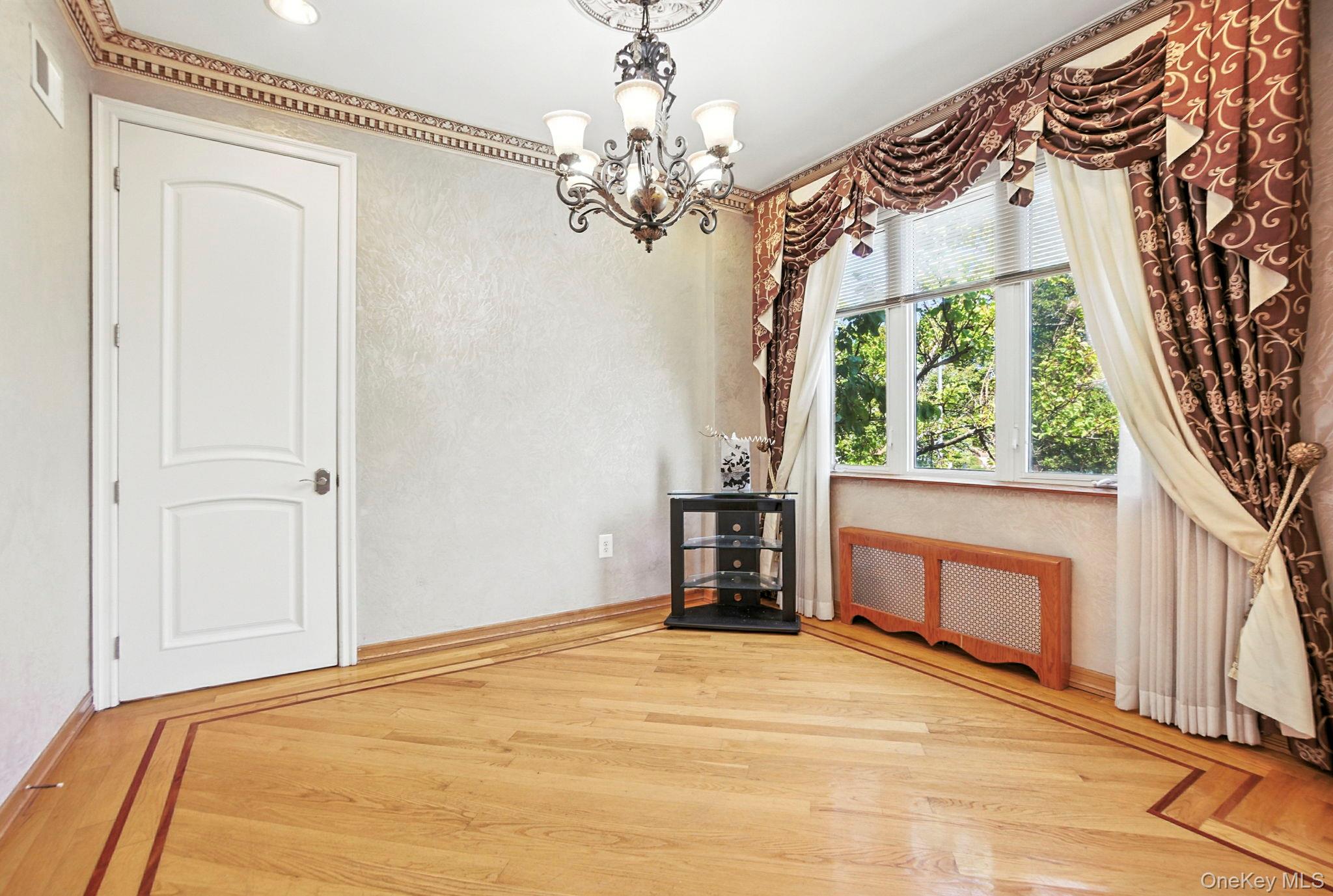 77-16 Kew Forest Lane Queens, NY 11375 - Photo 9 of 28 a view of empty room with a fireplace and chandelier