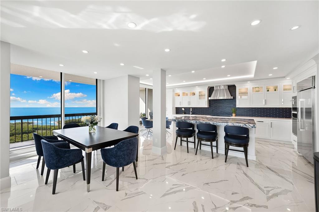6001 Pelican Bay Boulevard, Unit PHA Naples, FL 34108 - Photo 24 of 50 a dining hall with stainless steel appliances kitchen island a table and chairs