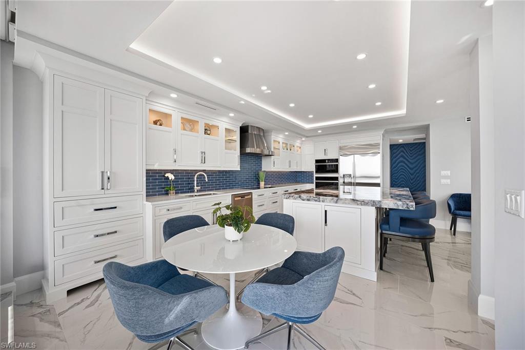 6001 Pelican Bay Boulevard, Unit PHA Naples, FL 34108 - Photo 28 of 50 a kitchen with a dining table chairs and view living room