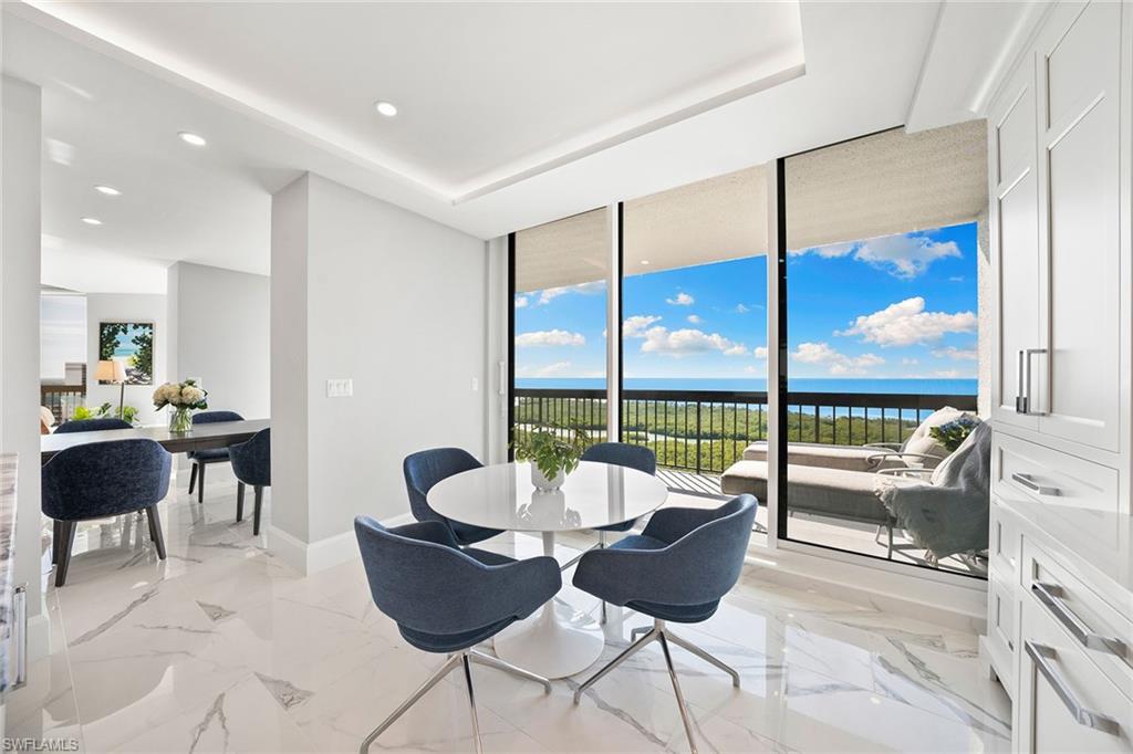 6001 Pelican Bay Boulevard, Unit PHA Naples, FL 34108 - Photo 29 of 50 a dining room with furniture a chandelier and wooden floor