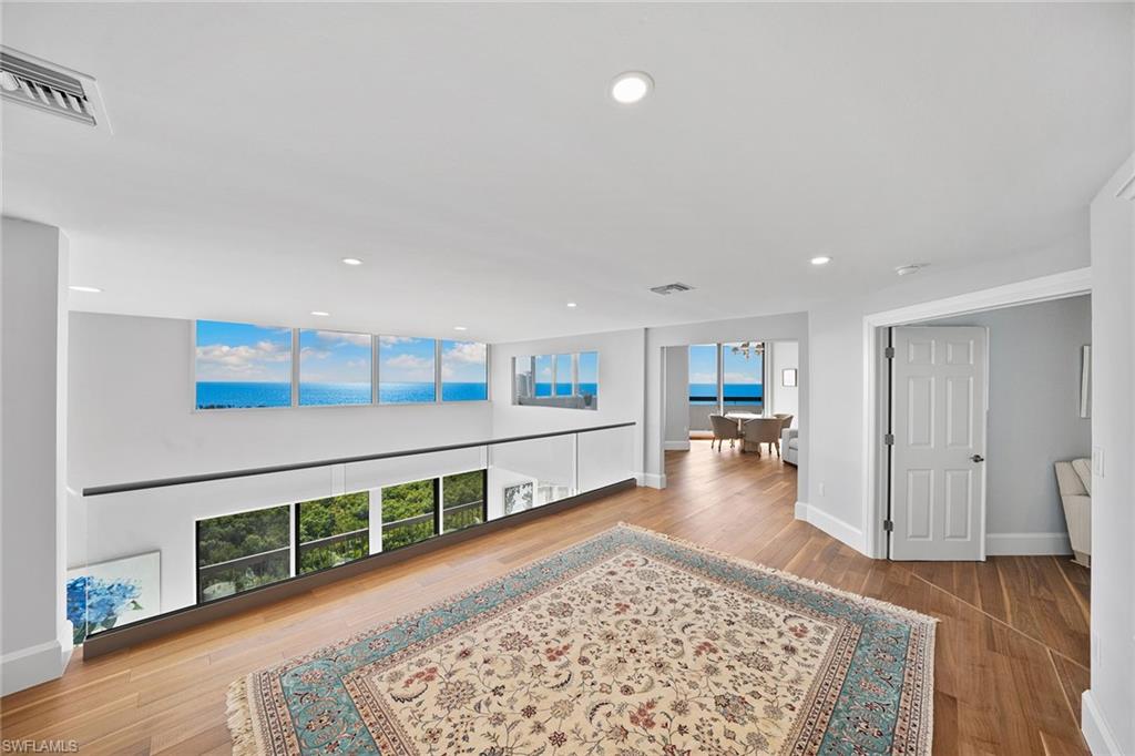 6001 Pelican Bay Boulevard, Unit PHA Naples, FL 34108 - Photo 38 of 50 a living room with wooden floor and a rug
