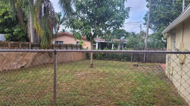 a view of a backyard with large trees and wooden fence