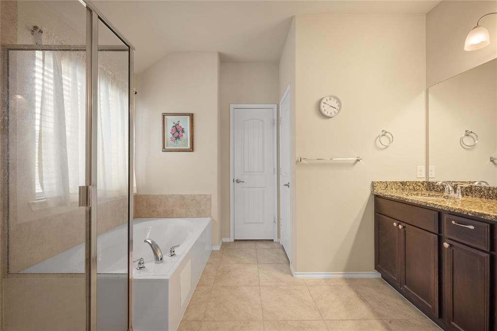 520 Rustic Oak Lane McKinney, TX 75072 - Photo 16 of 30 Bathroom featuring a full-size bathtub, glass-enclosed shower, dual vanity with undermount sinks, stone countertop, and tile flooring
