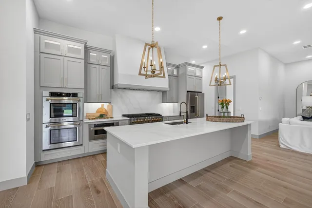 a large kitchen with stainless steel appliances a sink a stove a refrigerator and cabinets