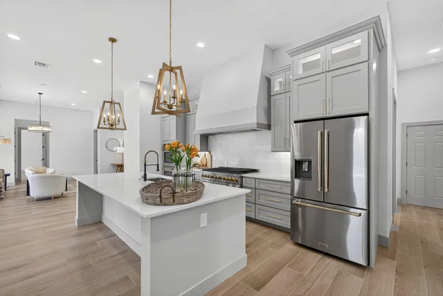 a kitchen with a refrigerator a sink dishwasher a stove and white cabinets with wooden floor