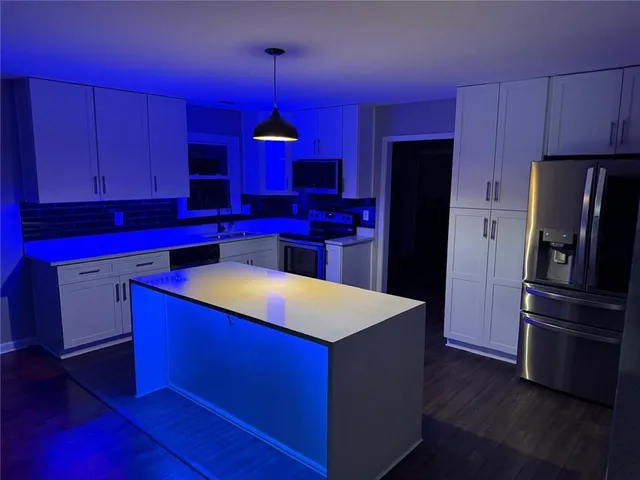 a view of a kitchen with wooden floor and electronic appliances