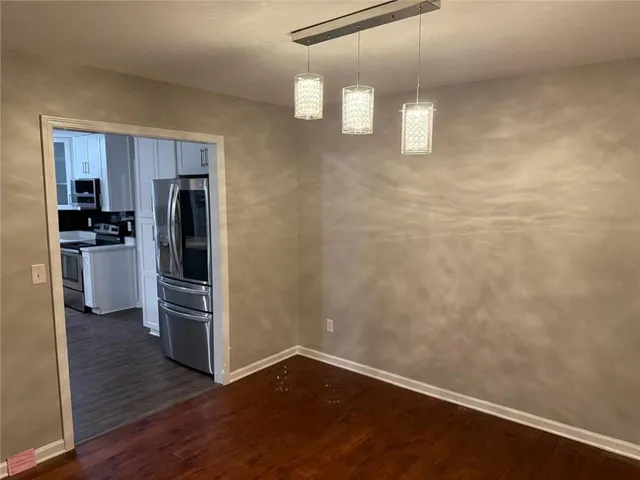 an empty room with wooden floor closet and windows