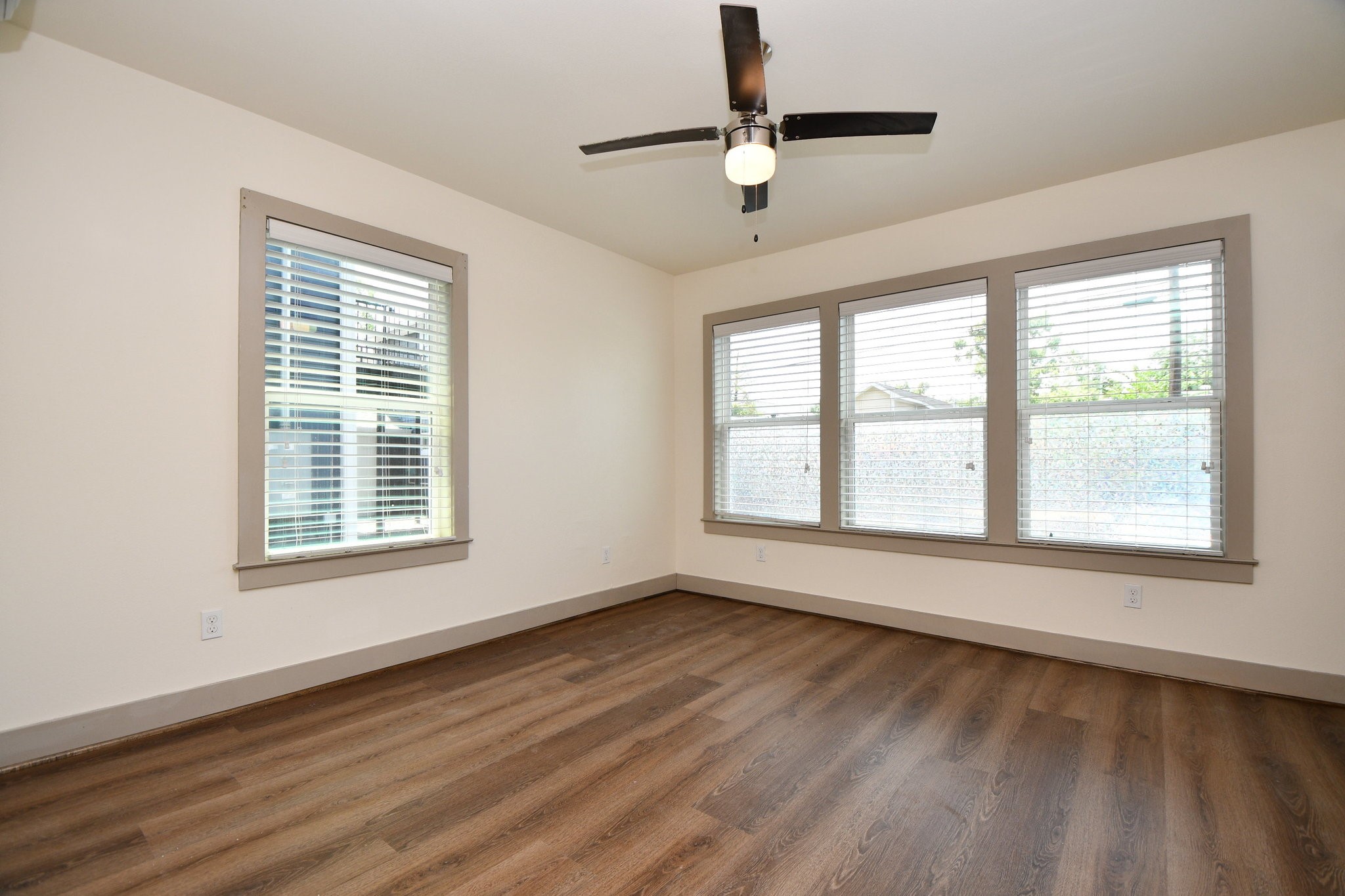 1011 Enid Street, Unit 2 Houston, TX 77009 - Photo 7 of 14 Bright bedroom with large windows, modern wood-style flooring, and a ceiling fan with light.