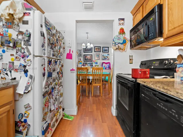 a kitchen with stainless steel appliances granite countertop a refrigerator a stove and wooden floor