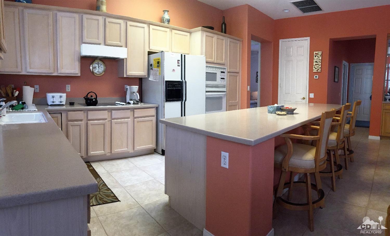 37235 Skycrest Road Palm Desert, CA 92211 - Photo 15 of 34 a kitchen with stainless steel appliances kitchen island granite countertop a table chairs in it and wooden floors