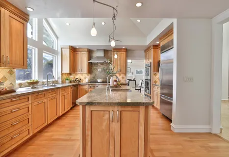 a large kitchen with kitchen island a large counter top space a sink stainless steel appliances and cabinets