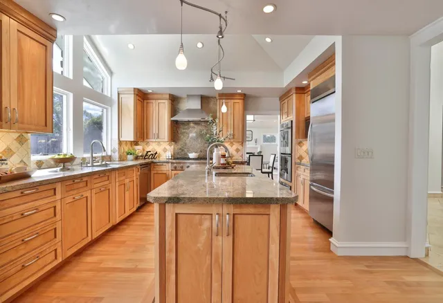 a large kitchen with kitchen island a large counter top space a sink stainless steel appliances and cabinets