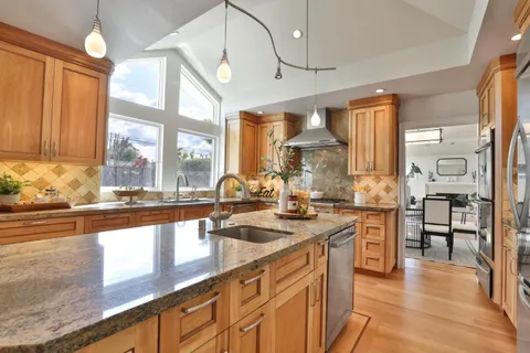 a kitchen with stainless steel appliances granite countertop a sink a stove and a wooden floors